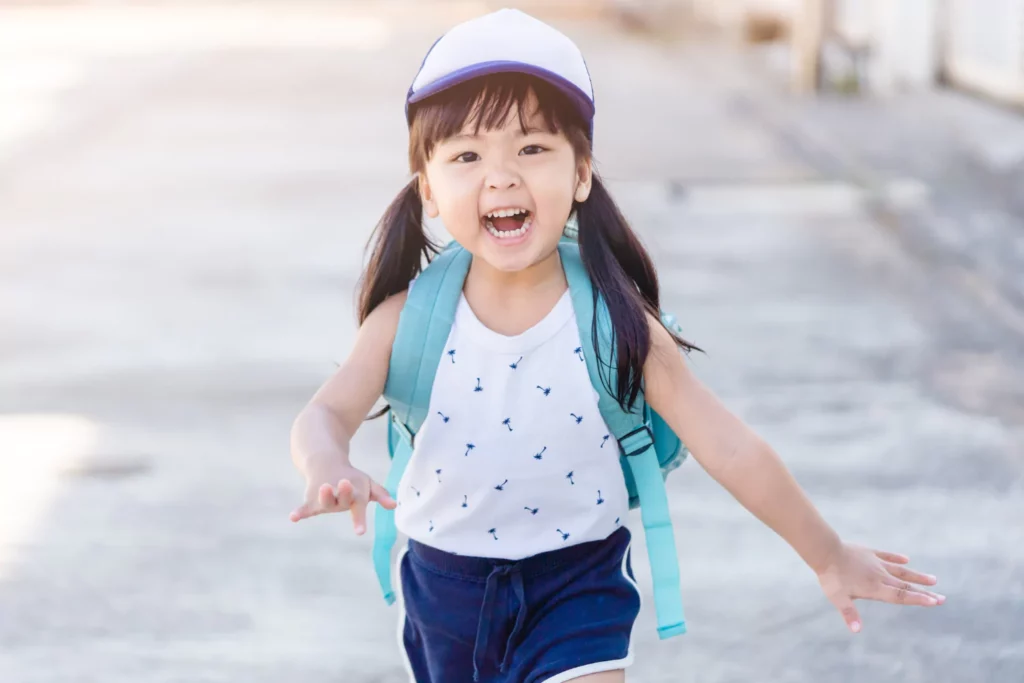 Young girl with backpack smiling as she runs