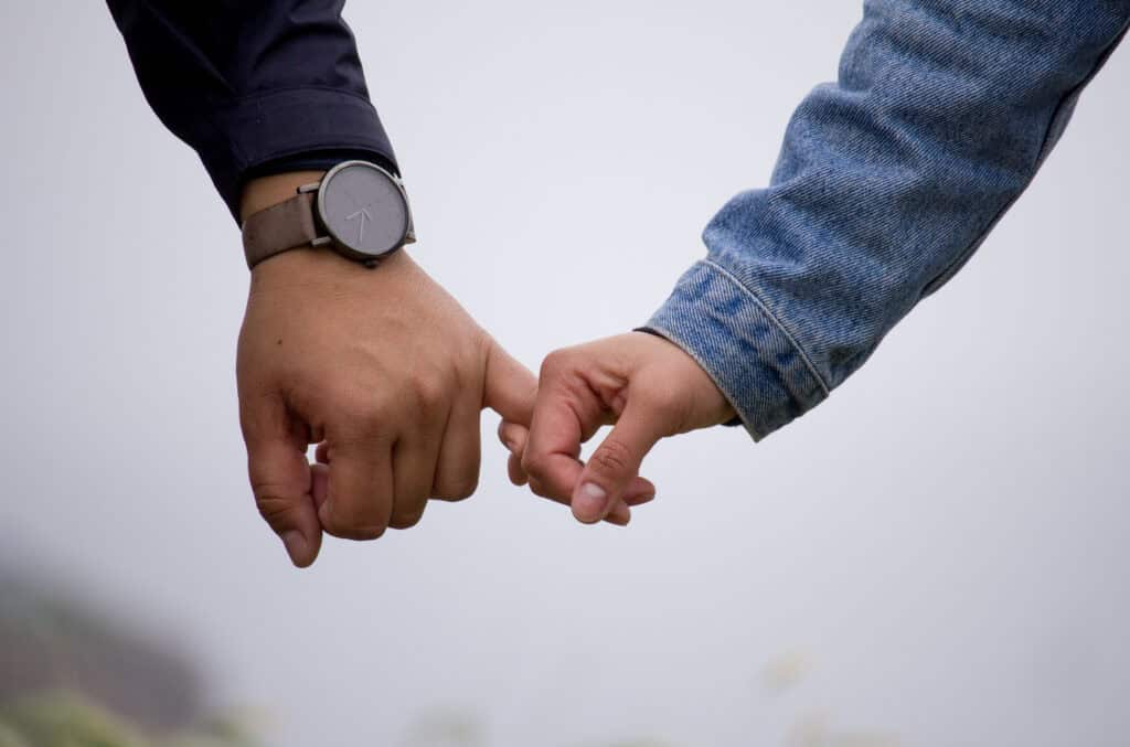 man and woman hands holding pinkies