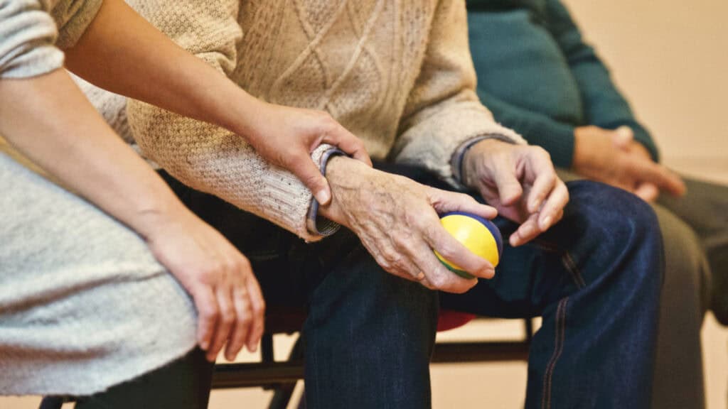older man holding ball, person holding his hand