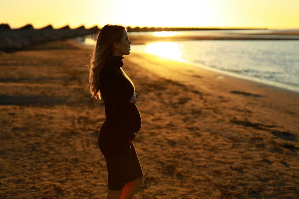 Young pregnant woman on beach at sunset