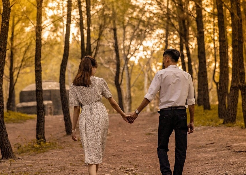 couple walking and in hand through woods fall
