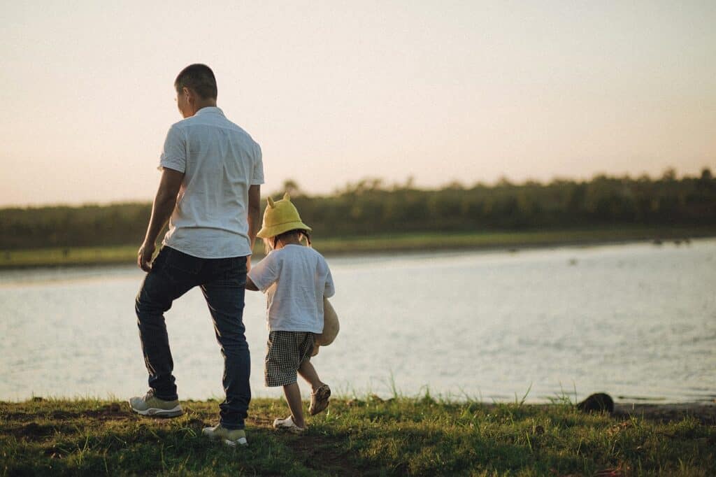father son walking hand in hand by river