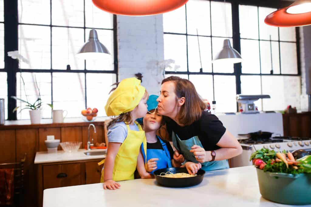 mom eating and cooking pasta with two young kids