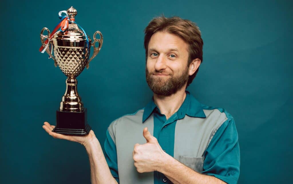 Man holding trophy grinning thumbs up