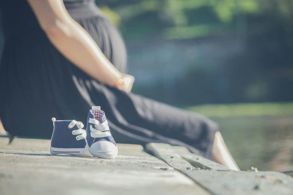 pregnant woman in background baby shoes in foreground