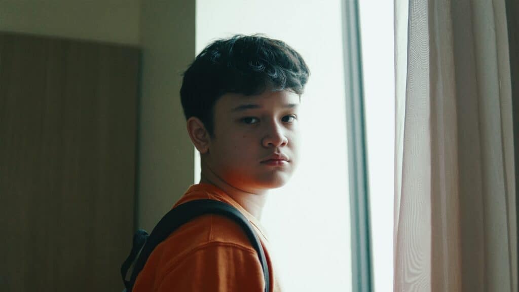 boy frowning in front of window