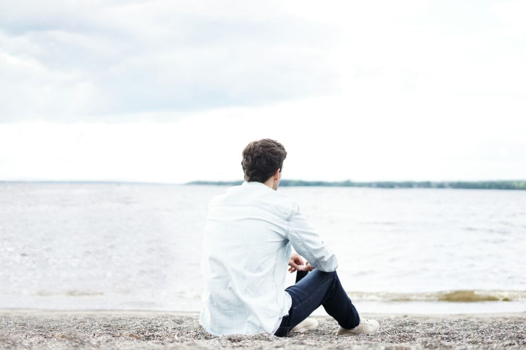 Man sitting on beach back to camera