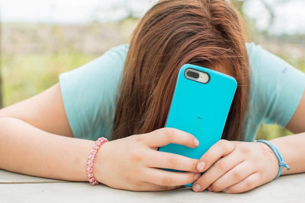 Teen covering face with her phone