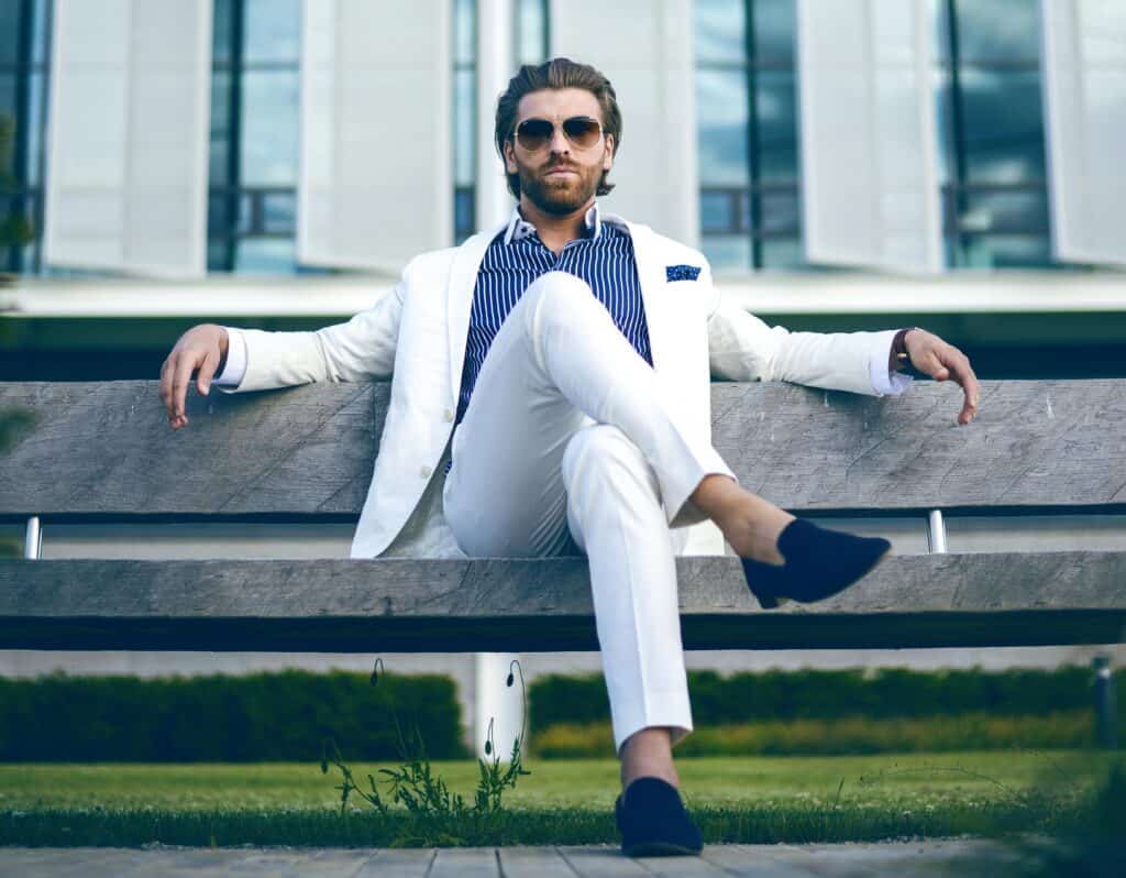 man in fancy suit sunglasses sitting on bench