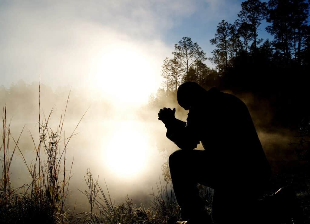 man in hazy meadow praying