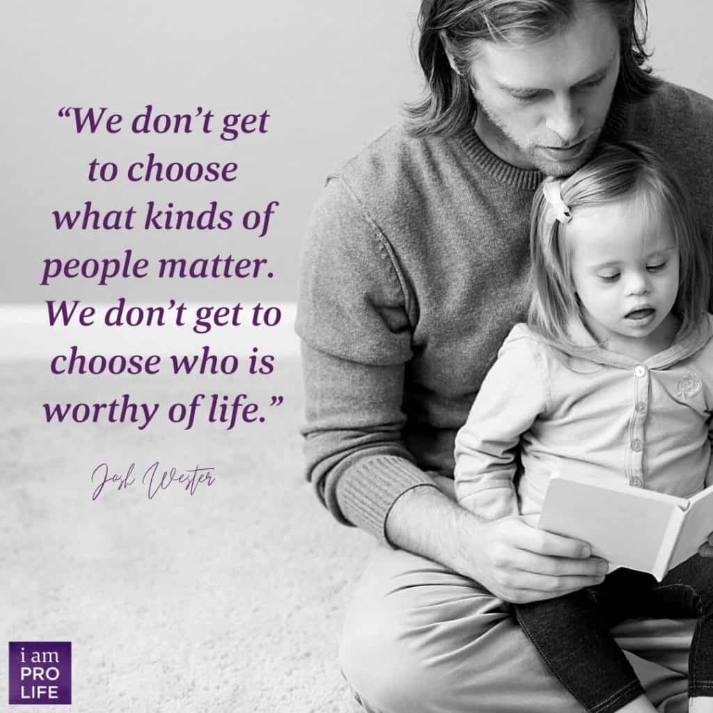 A father holds his daughter who has Down syndrome as he prays a pro-life prayer