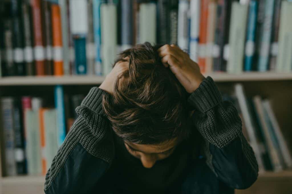 boy in library head in hands sad